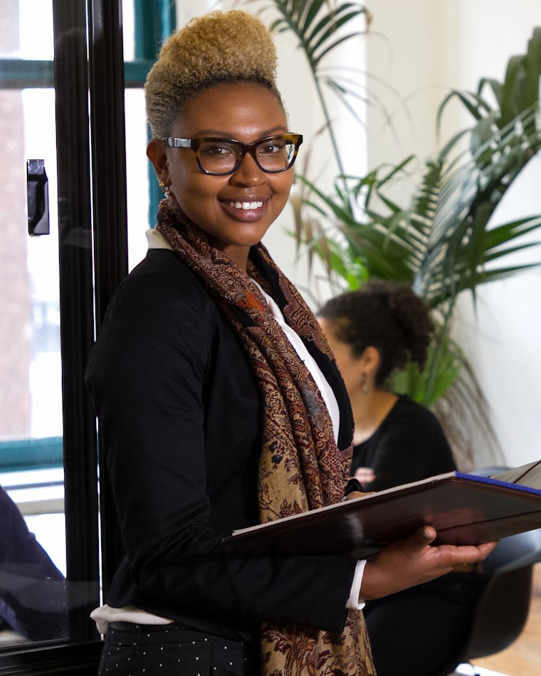 Placeholder photograph of a bookkeeper standing in an office holding a client folder