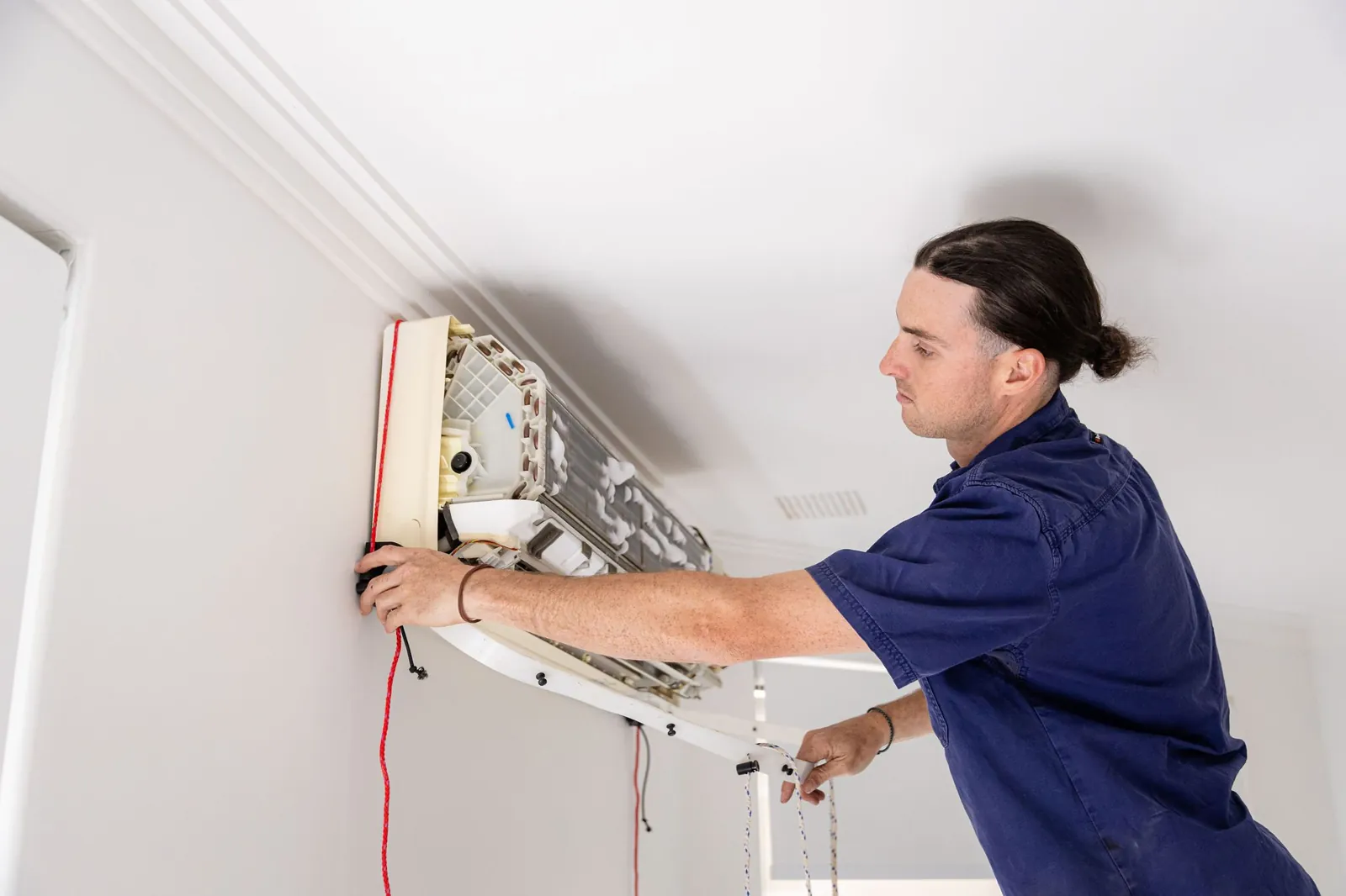 A Handcock electrician installing a split system air conditioner
