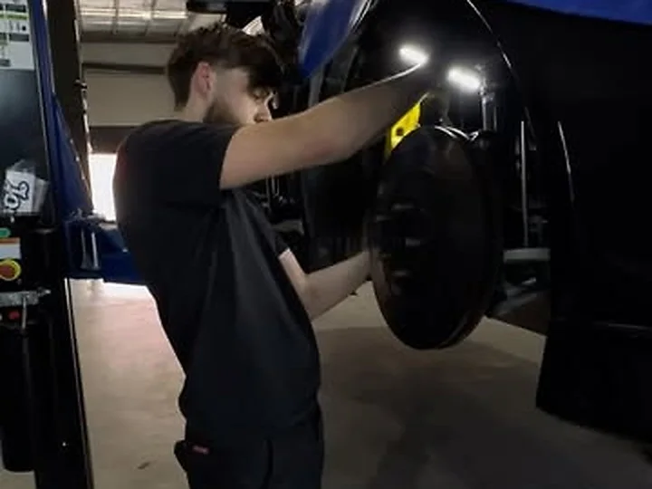 A HazTech mechanic working on the brakes of a car on the hoist