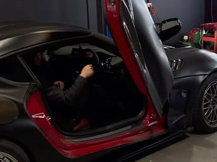 A sports coupe with its door open in the HazTech workshop
