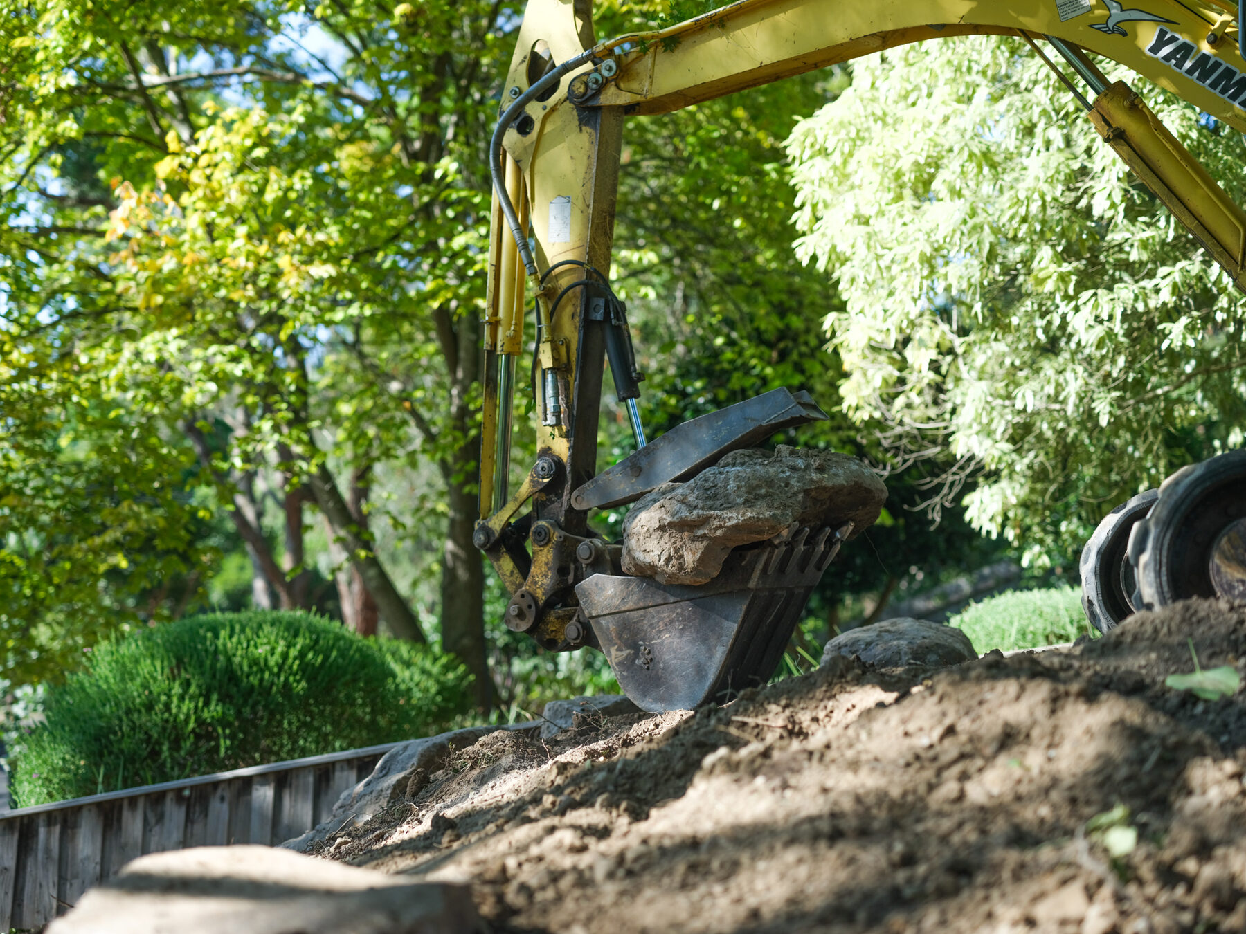 Excavator bucket lifting a boulder into place