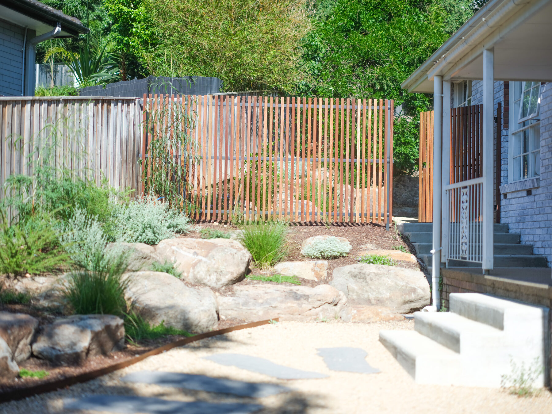 Gravel courtyard with bluestone stepping stones and a rock wall