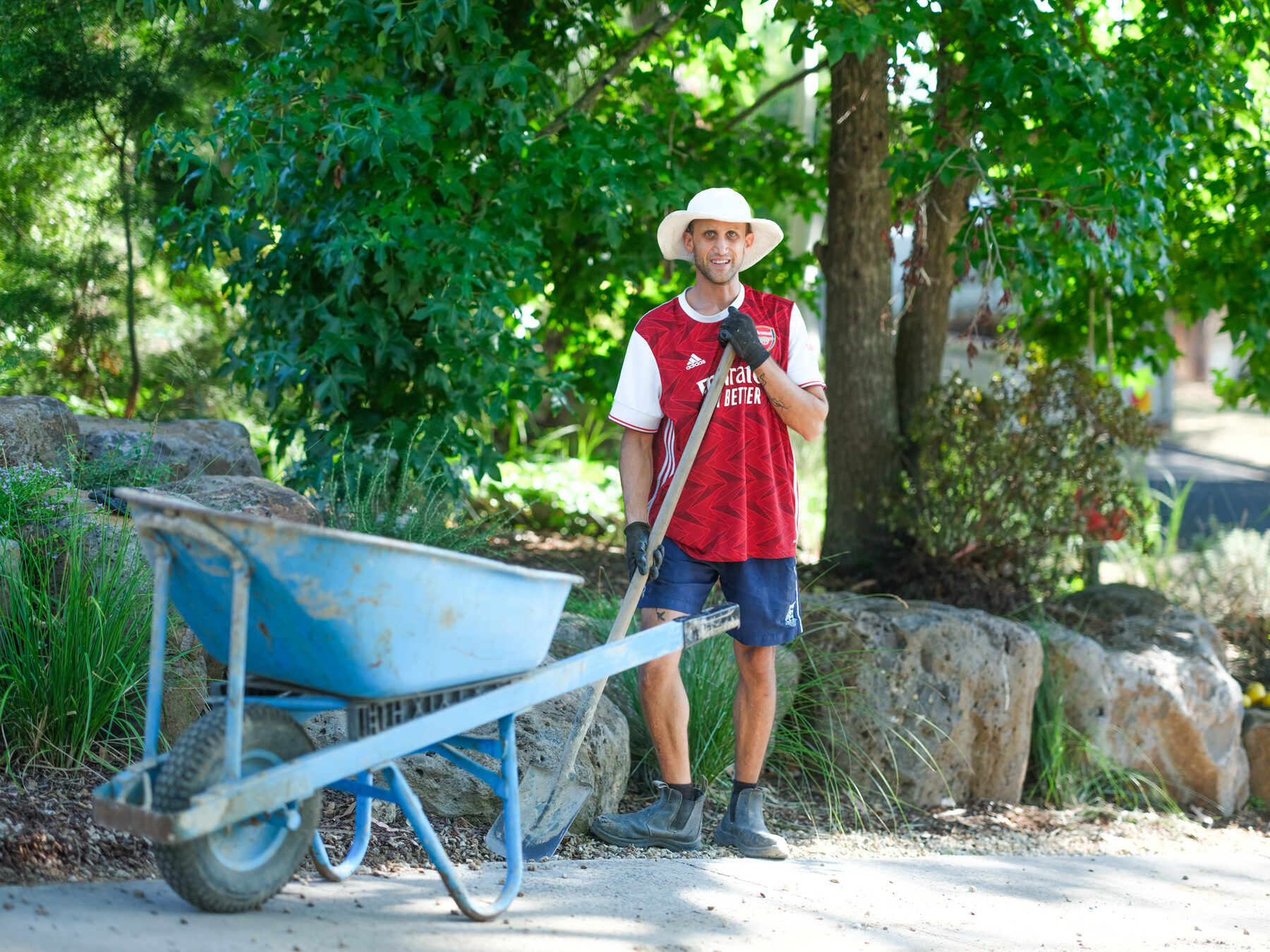 A landscaper with a wheelbarrow and shovel on a finished garden path
