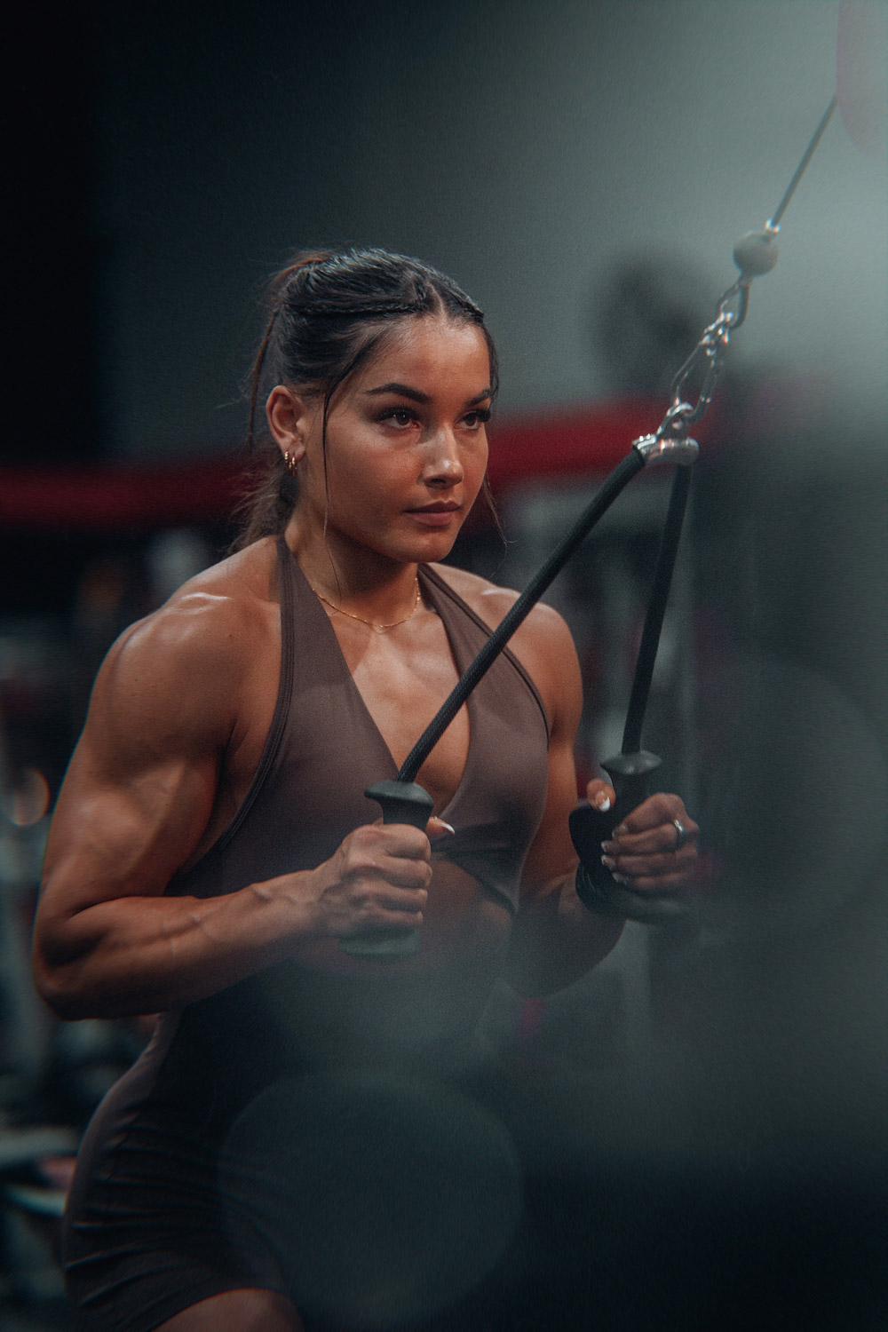 Muscular woman training on a cable machine in a moody dark gym