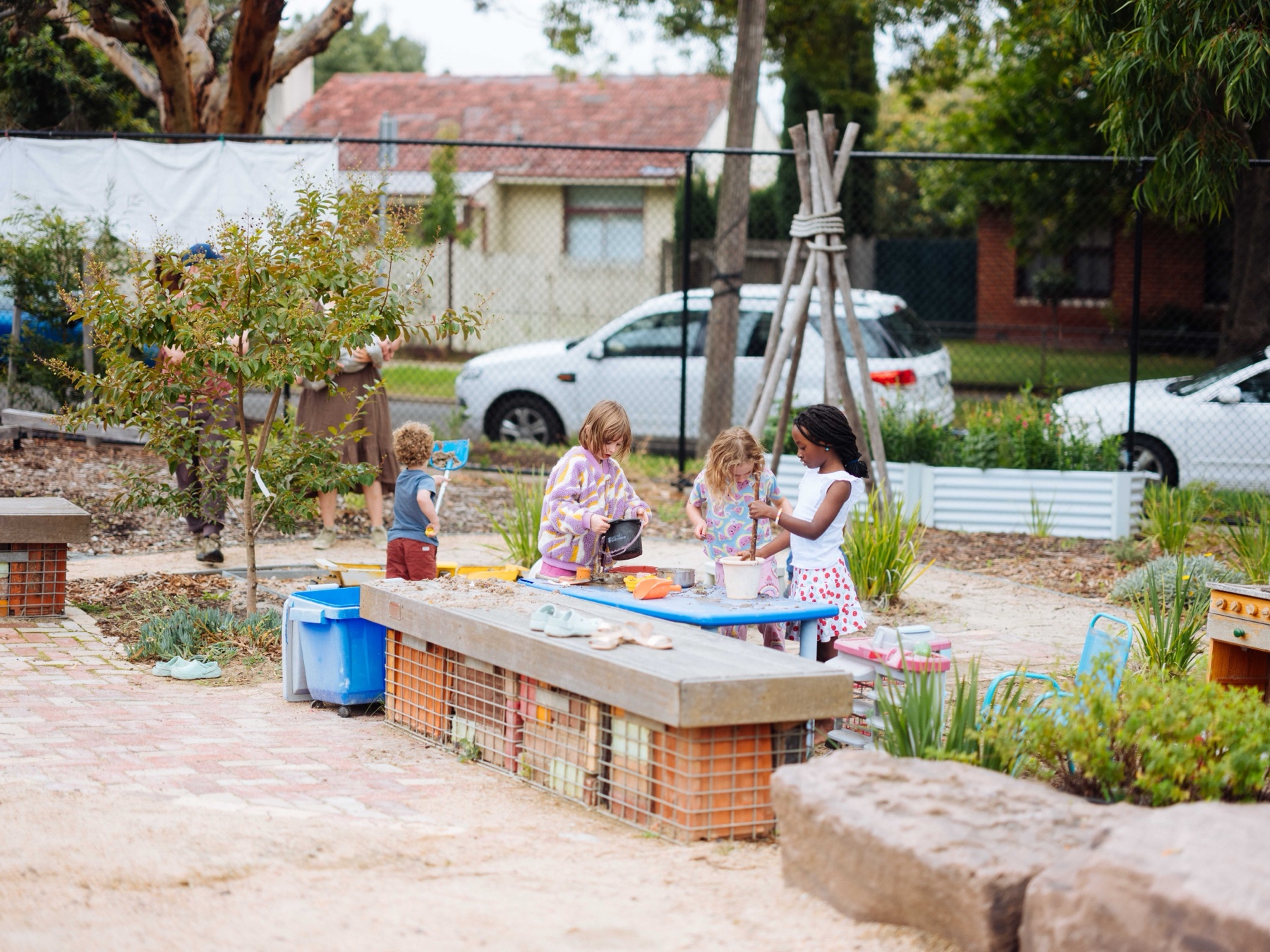 Young children playing together at the garden sand table