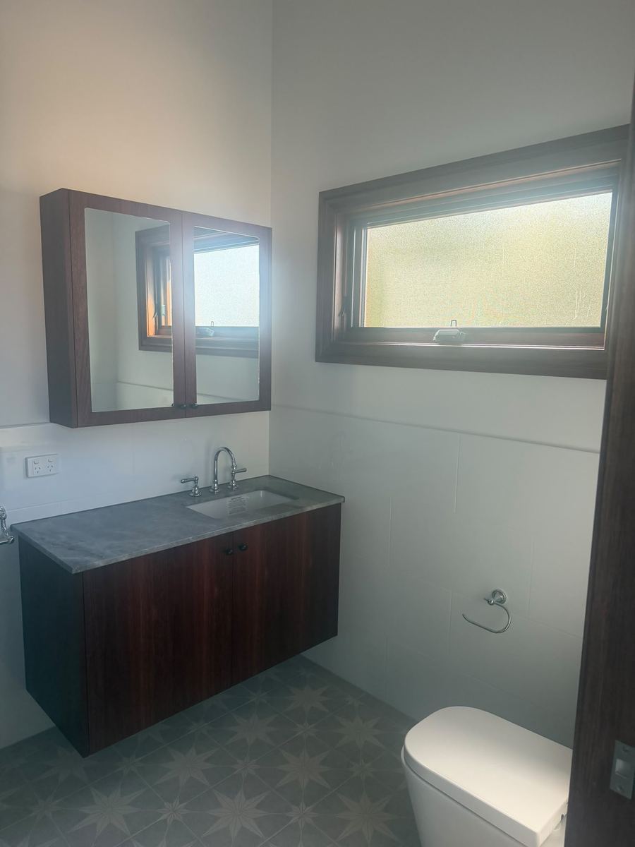 Bathroom with a timber vanity, stained window frame and patterned floor tiles