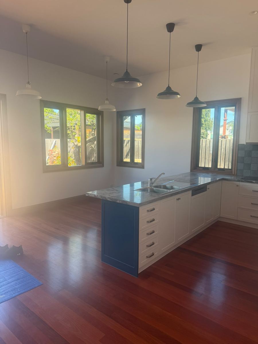 Open kitchen and living area with pendant lights, white cabinetry and a blue island