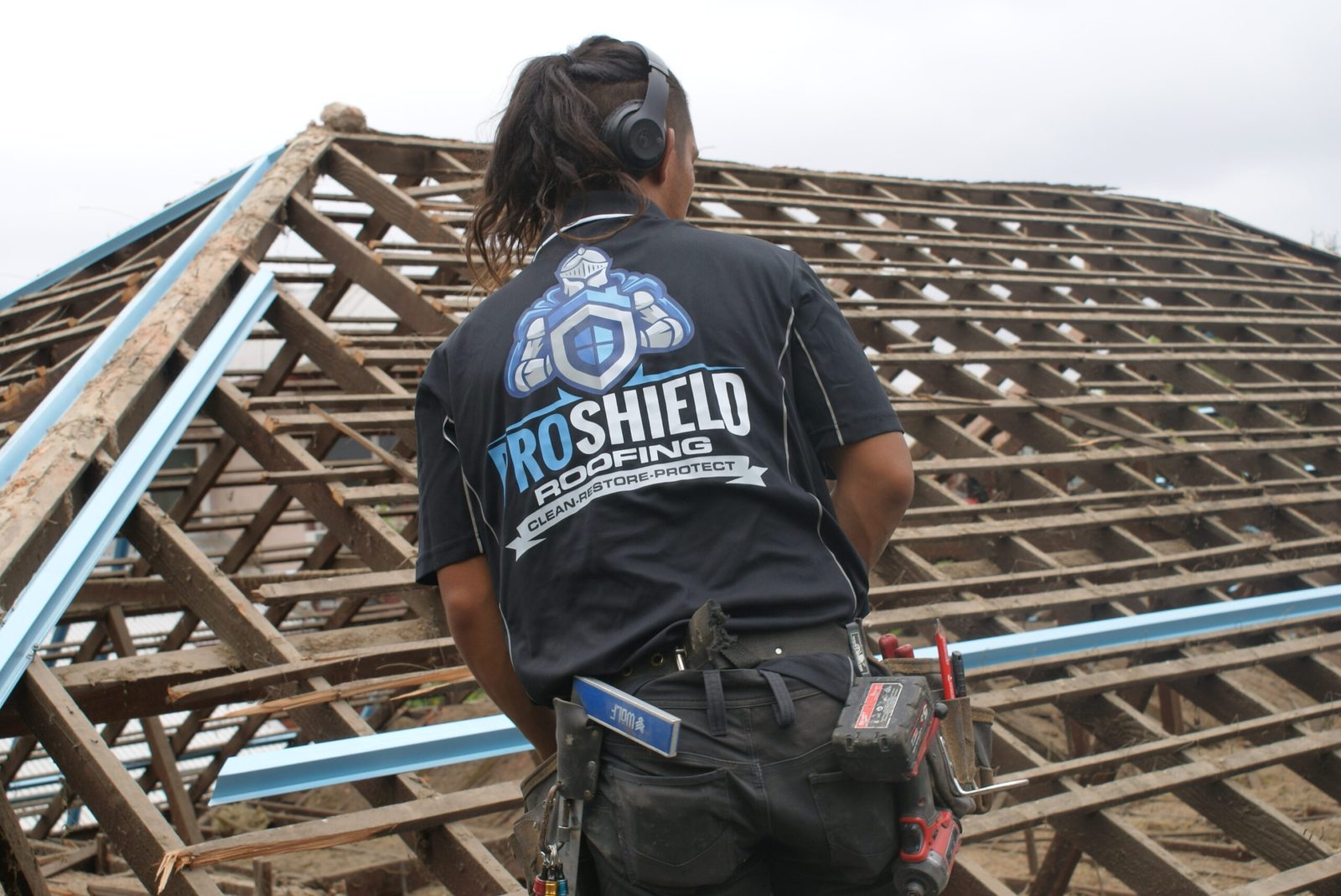 A Pro Shield roofer installing new battens across a stripped roof frame