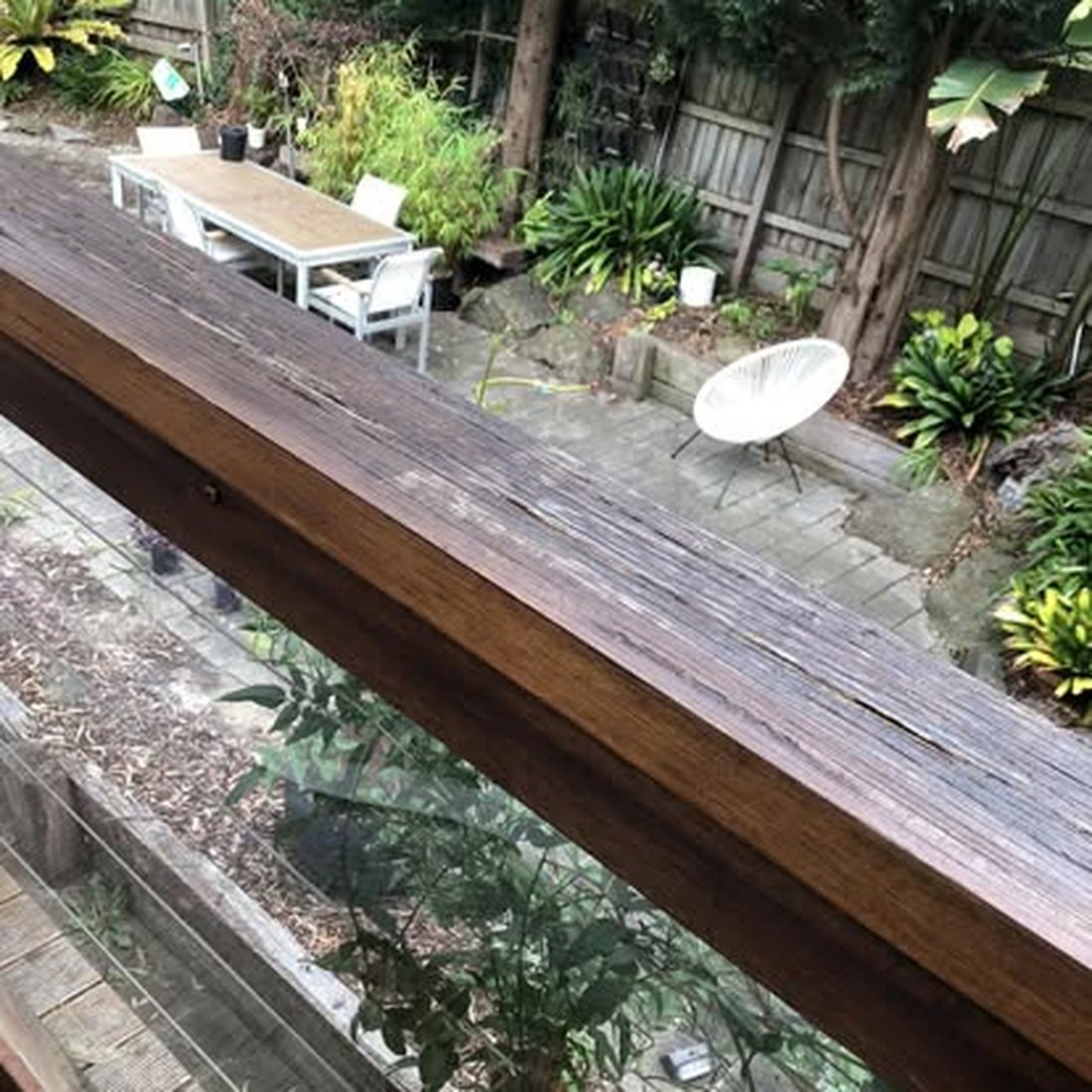 Long timber deck with an outdoor dining setting and garden beyond