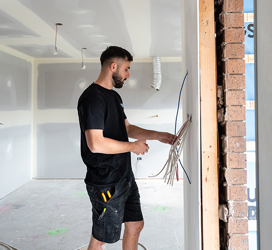 A Right 1 Group electrician running cable at a doorway