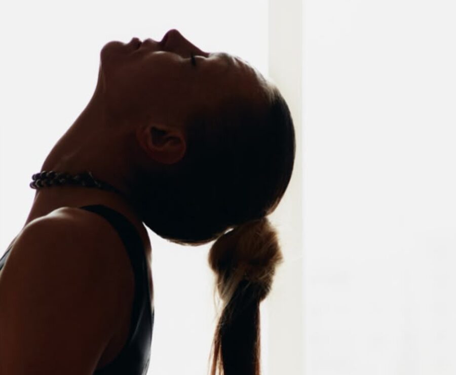 A woman in a yoga back bend, lit by a bright window